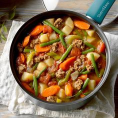 a bowl filled with meat and veggies on top of a white napkin next to a spoon