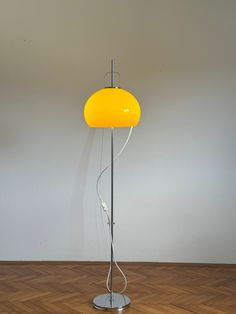 a yellow floor lamp sitting on top of a hard wood floor