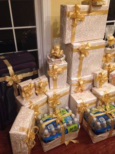 many wrapped presents are stacked on top of each other with gold ribbons and bows around them