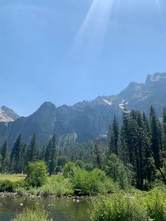 the sun shines on mountains and trees near a river