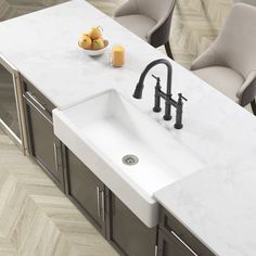 a white sink sitting under a kitchen faucet next to a bowl of fruit