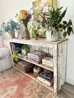 an old wooden shelf with flowers and books on it