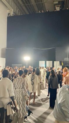 a large group of people standing in front of a black screen at a fashion show