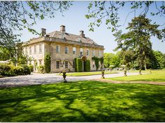 a large house with lots of windows in the middle of a green lawn and trees