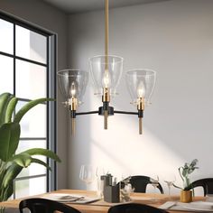 a modern chandelier hangs over a dining room table with black chairs and a potted plant