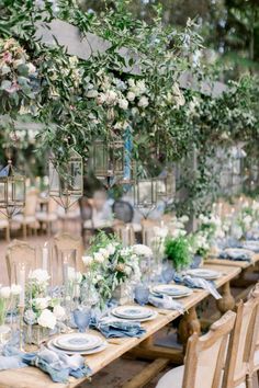 a long table set with blue and white place settings, greenery hanging from the ceiling