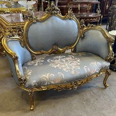 an ornately decorated couch sitting in a room next to other antique furniture and mirrors