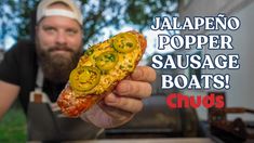 a man holding up a piece of pizza with jalapeno popper sausage on it