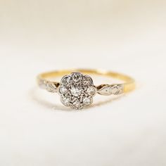 an antique diamond cluster ring in yellow and white gold, on a plain surface with no background