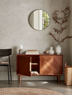 a room with a round mirror and wooden furniture