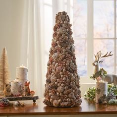 a christmas tree made out of pine cones on a table next to other holiday decorations