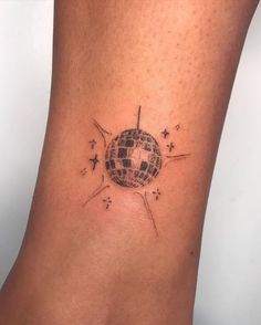 a woman's foot with a small tattoo on the side of her leg that has a disco ball and stars all over it