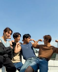 four young men posing for the camera with their arms in the air