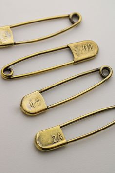 three antique gold hair clips with numbers on them