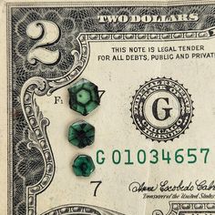 three emeralds on top of a twenty dollar bill