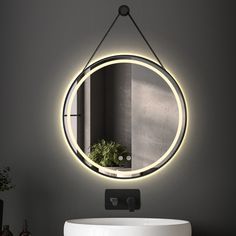 a bathroom sink with a round mirror above it and a plant in the reflection on the wall