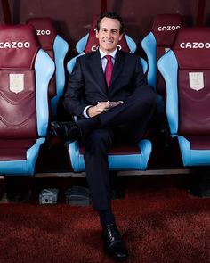 a man in a suit and tie sitting on the sidelines of a stadium seat