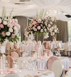 the tables are set with white linens, pink flowers and gold vases for centerpieces