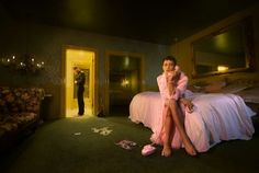 a woman sitting on top of a bed in a bedroom next to a man standing