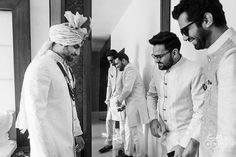 two men in turbans are looking at something on a table while another man stands behind them