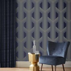 a blue chair sitting in front of a window next to a gold vase on top of a wooden floor