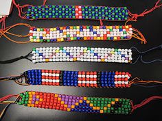 four beaded bracelets are lined up on a black table with red, white, and blue beads