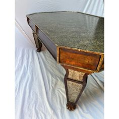 an old table with marble top sitting on a white sheet