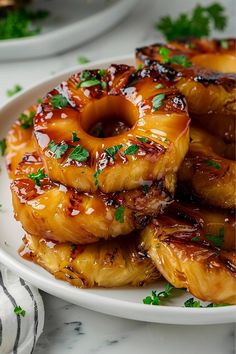 grilled pineapple rings on a white plate with parsley sprinkled around them