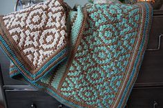 two crocheted blankets sitting on top of a dresser next to a christmas tree