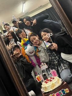 a group of people posing for a photo in front of a mirror with a birthday cake