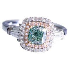 a fancy ring with an emerald and white diamond in the center on a white background