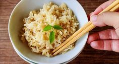 someone is holding chopsticks over a bowl of rice