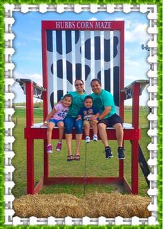 three people sitting on a giant chair in the grass