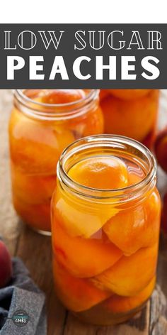 two jars filled with peaches sitting on top of a wooden table next to apples