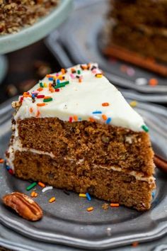 a slice of carrot cake with white frosting and sprinkles on a plate