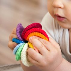 a baby is holding a bunch of colorful crochet pieces