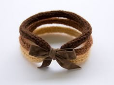 three different colored bracelets with a brown bow on each one and a beige ribbon on the other