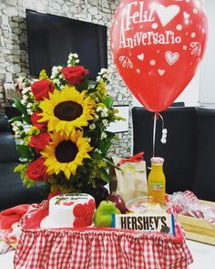 a table topped with a cake and flowers next to a red heart - shaped balloon