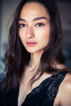 a close up of a person wearing a black dress and posing for the camera with long hair