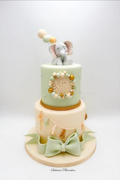 a multi layer cake decorated with an elephant and baby's name on the top