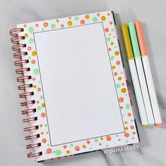 an open notebook with two pens on top of it and a notepad next to it