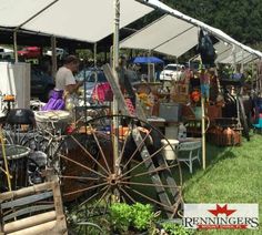 an outdoor flea market with lots of items on the grass and people looking at them