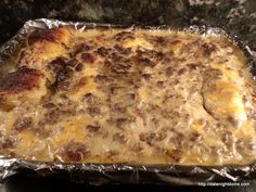 a casserole covered in cheese and meat sitting on top of an oven pan