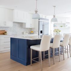 a kitchen with white cabinets and blue island in front of the countertop, surrounded by bar stools