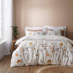 a bed with white and orange flowers on it in a room next to a window