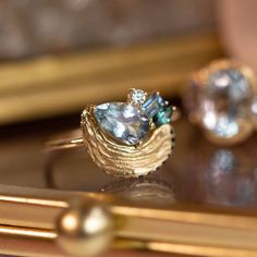 two rings sitting on top of a table next to pearls and other jewelry items in front of a mirror