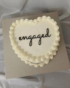 a heart shaped cake with the word engaged written in cursive writing on it