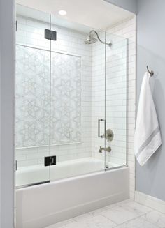 a bathroom with a glass shower door and white tile flooring, along with a towel hanging on the wall