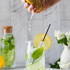 someone is pouring water into a glass with lemon and mint