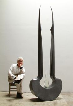 a man sitting on a chair next to a sculpture